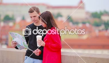 Avrupa 'da tatil yapan genç turist çift mutlu bir şekilde gülümsüyor. Şehir haritası olan beyaz bir aile cazibe arıyor.