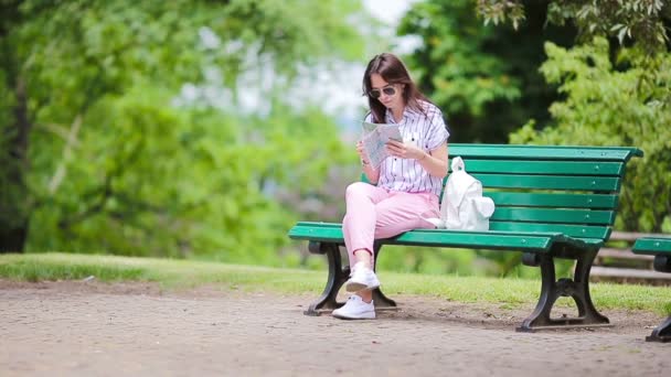 Gelukkige jonge vrouw met een plattegrond in Europa. Reizen toerist vrouw met kaart in het park buiten tijdens vakantie — Stockvideo