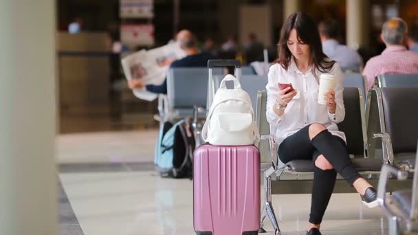 Passagier van een luchtvaartmaatschappij in een luchthavenlounge die op een vliegtuig wacht. Blanke vrouw op zoek naar tijd in de wachtkamer — Stockvideo