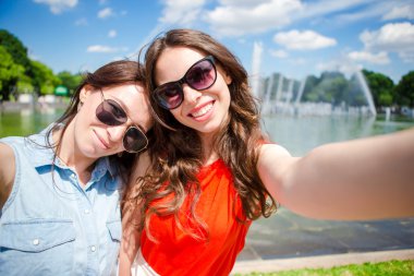 Beyaz kızlar selfie arka plan büyük çeşme yapıyor. Tatilde seyahat eden genç turist arkadaşları mutlu gülümseyerek.