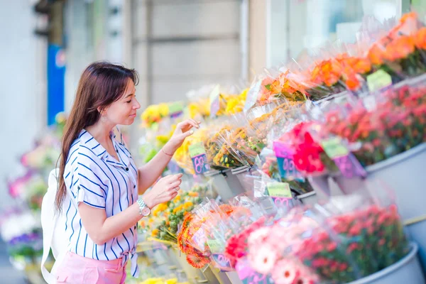 Beautiful young woman with long hair selecting fresh flowers at european market — Stock Photo, Image