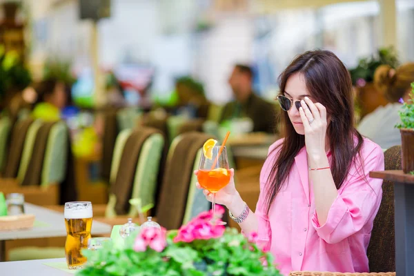Mladá krásná žena sedí v kavárně venku a pije chutný koktejl. Šťastný turista vychutnat evropské svátky na openair restarteta — Stock fotografie
