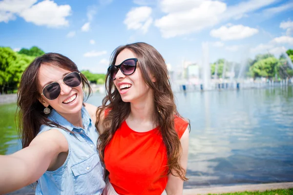 Caucasian girls making selfie background big fountain. Young tourist friends traveling on holidays outdoors smiling happy.