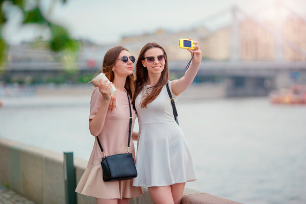 Young tourist friends traveling on holidays outdoors smiling happy. Caucasian girls making selfie background big bridge