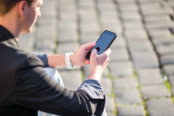 De close-up van mannelijke handen houdt zijn mobieltje buiten op straat. Man met mobiele smartphone. — Stockfoto