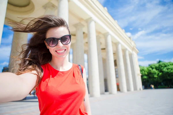 Young caucasian woman making selfie on attractions background outdoors. Happy girl enjoy her weekend in european city — Stock Photo, Image