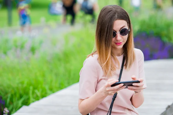 Toeristische meisje verzenden messgae door smartphone op zomer vakantie. Jonge aantrekkelijke vrouw met mobiele telefoon buitenshuis genieten van vakantie reisbestemming in het toerisme en verkennen concept — Stockfoto