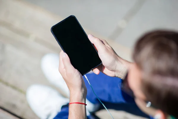 Närbild av mobiltelefon visas i manliga händer utomhus på gatan. Man använder mobil smartphone. — Stockfoto