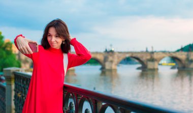 Genç Kafkas kadın selfie The Charles Bridge arka plan yapma. Mutlu kız zevk onu hafta sonu Avrupa şehirde