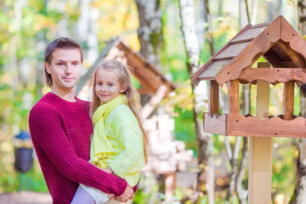 Mladý otec gumtyp malou dceru krmit ptáky v podzimním parku venku — Stock fotografie