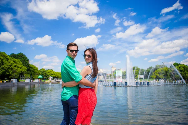 Junges touristisches Paar, das im Urlaub in Europa unterwegs ist, lächelt glücklich. Kaukasische Mädchen und Mann Hintergrund des Brunnens — Stockfoto