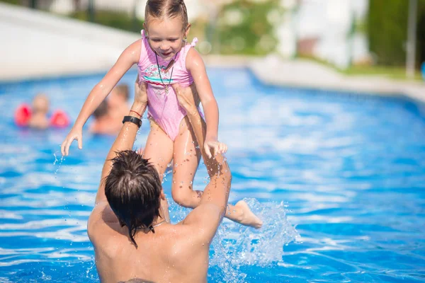 Young dad and little daughter playing in swimming pool enjoying summer vacation — Stock Photo, Image