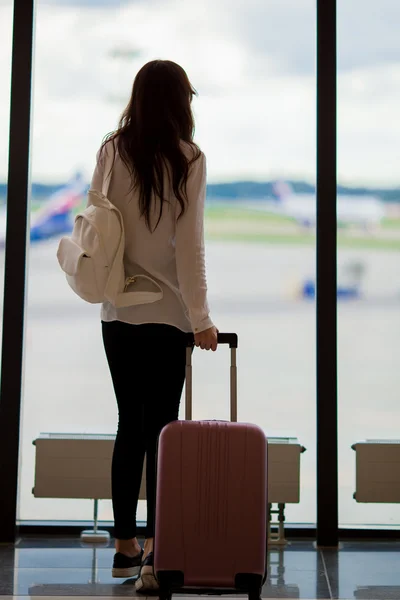 Mujer joven cerca de la ventana en un salón del aeropuerto esperando aviones de vuelo —  Fotos de Stock