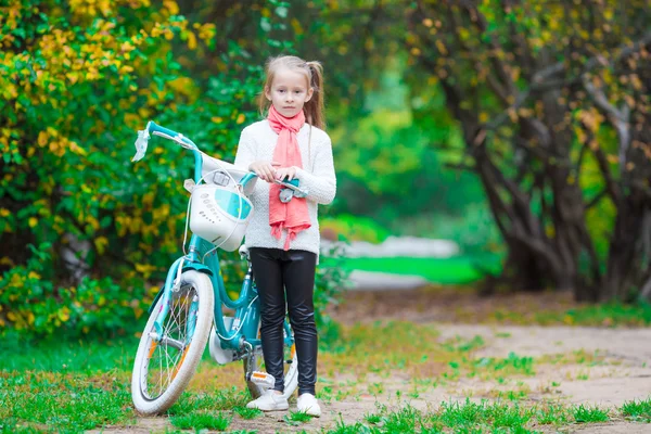 Adorabile ragazza in sella a una bicicletta in bella giornata d'autunno all'aperto — Foto Stock