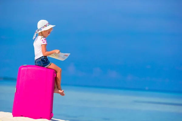 Niña adorable con gran maleta rosa y mapa de la isla en la playa blanca —  Fotos de Stock