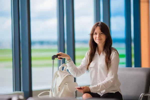 Flugpassagier in einer Flughafenlounge, die auf ein Flugzeug wartet. Kaukasierin mit Smartphone im Wartezimmer — Stockfoto