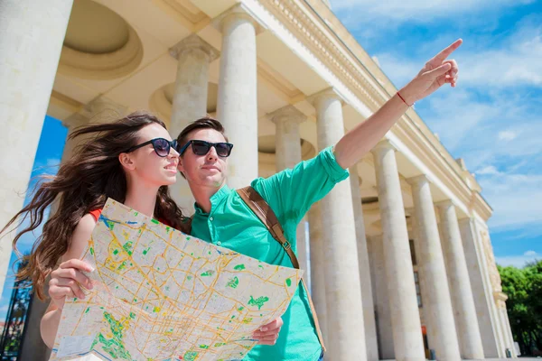 Jóvenes amigos turistas que viajan de vacaciones en Europa sonriendo felices. Familia caucásica con mapa de la ciudad en busca de atracciones — Foto de Stock