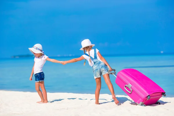 Little tourists girls with big suitcase on tropical white beach. Travel concept. — Stock Photo, Image
