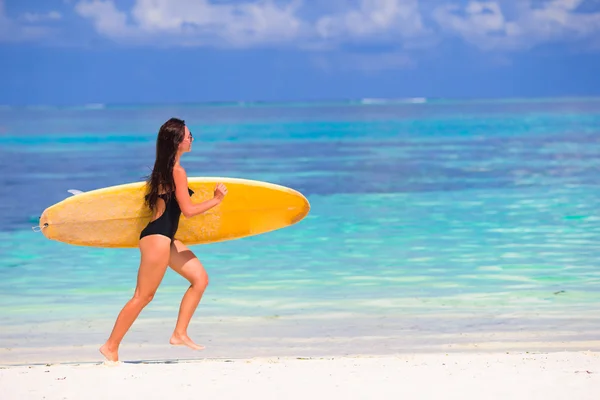 Gelukkig jonge surf vrouw runing op het strand met een surfplank — Stockfoto