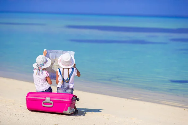 Kleine meisjes met grote koffer en kaart op tropisch strand — Stockfoto