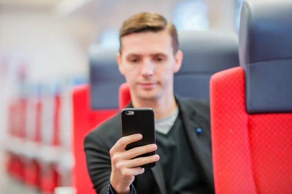 Jovem viajando de trem. Turista escrevendo uma mensagem no celular enquanto viaja de trem expresso — Fotografia de Stock
