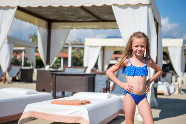 Adorável menina sorridente feliz em férias na praia perto de espreguiçadeiras — Fotografia de Stock