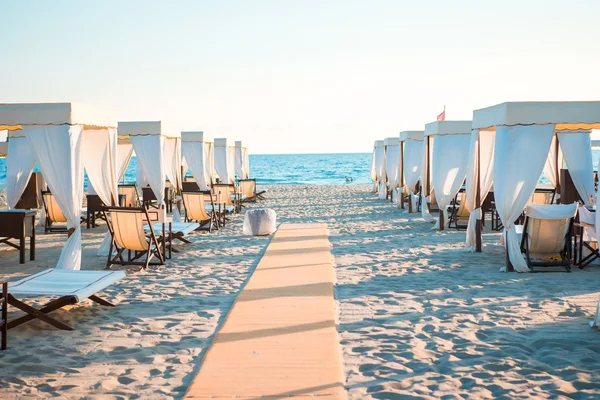 Tumbonas de madera frente a un mar turquesa a la luz de la tarde. Tumbonas en la famosa playa de arena italiana en Forte dei Marmi —  Fotos de Stock