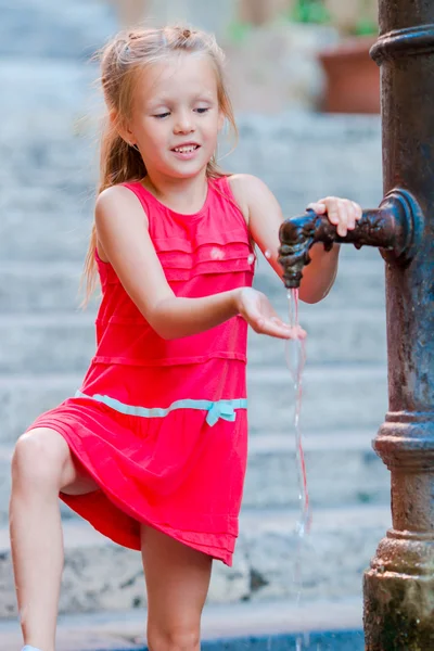 Liten söt flicka dricksvatten från kranen utanför på varm sommardag i Rom, Italien — Stockfoto