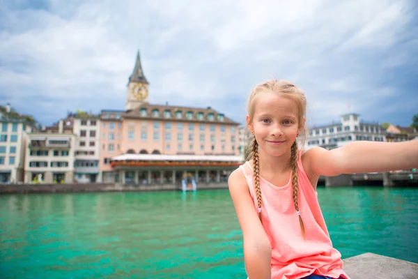 Adorable little girl taking selfie with mobile phone outdoors in Zurich, Switzerland. Closeup portrait of beautiful kid background of cute city — Stock Photo, Image
