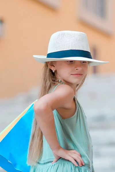 Portrait of adorable little girl walking with shopping bags outdoors in Rome. Fashion toddler kid in Italian city with her shopping — Stock Photo, Image