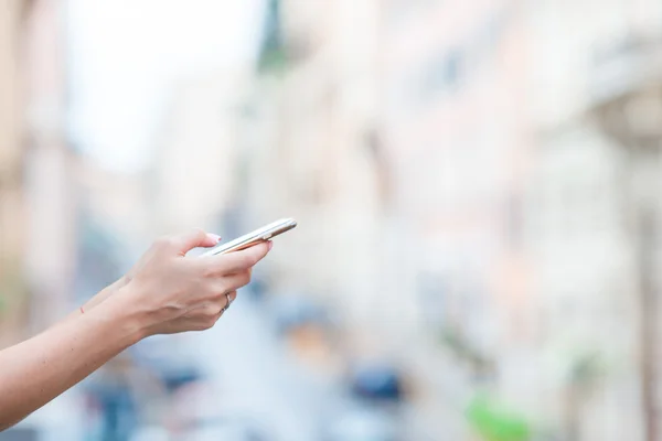 Close-up de mãos femininas segurando celular ao ar livre na rua. Mulher usando smartphone móvel . — Fotografia de Stock