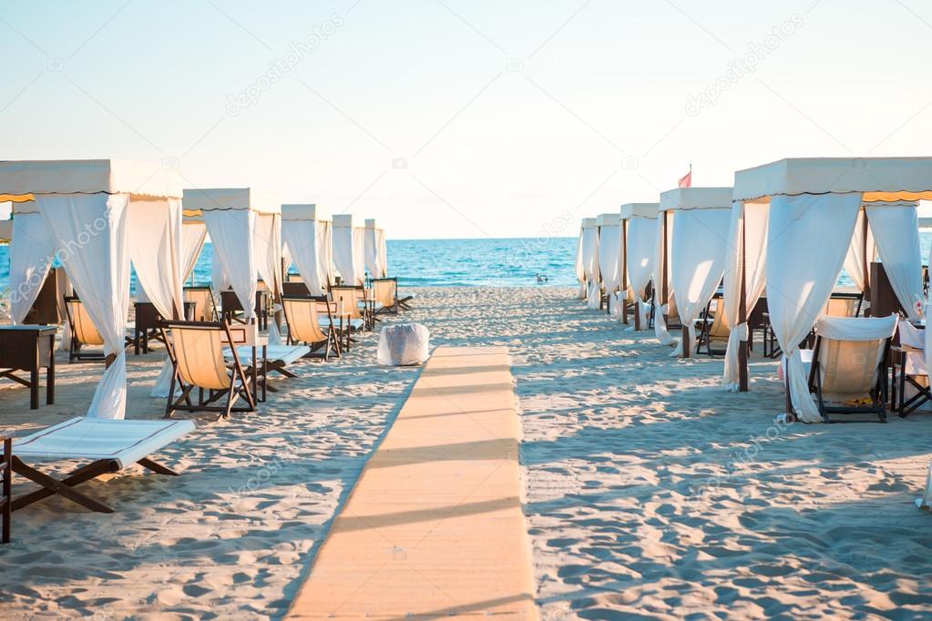 Wooden Sunbeds In Front Of A Turquoise Sea In The Evening
