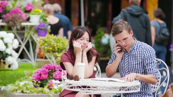Restaurant toeristen paar in outdoor cafe. jong meisje verdrietig op haar vriend omdat hij bezig is met klusjes — Stockvideo