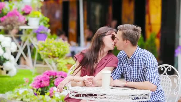 Para turystów restauracji w kawiarni na świeżym powietrzu. Młoda kobieta cieszyć się razem z mężem, podczas gdy mężczyzna czyta. — Wideo stockowe