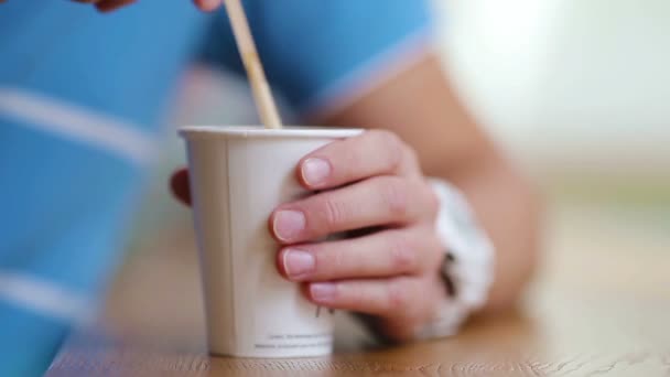 Primer plano de las manos masculinas agitar el azúcar en un vaso con café en la cafetería . — Vídeo de stock