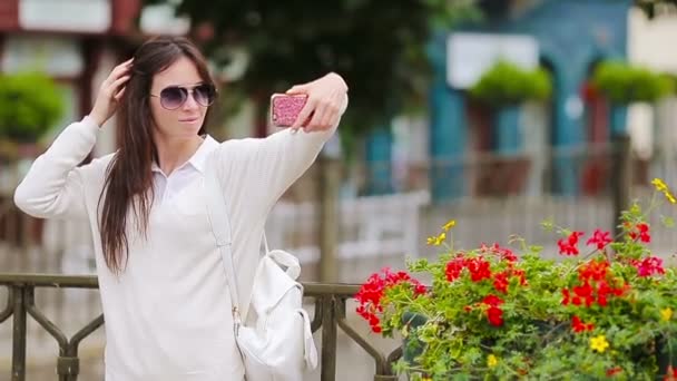 Junge Frau beim Selbstporträt hinter einem schönen Haus in einer europäischen Stadt. Kaukasische Touristin genießt ihren Sommerurlaub in Europa. — Stockvideo