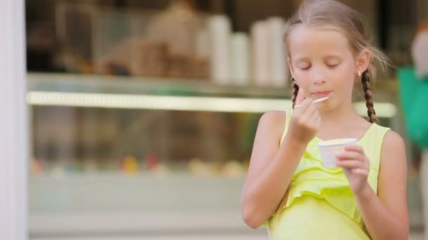 Entzückendes kleines Mädchen, das im Sommer draußen Eis isst. Nettes Kind genießt echtes italienisches Gelato in der Nähe von Gelateria in Rom — Stockvideo