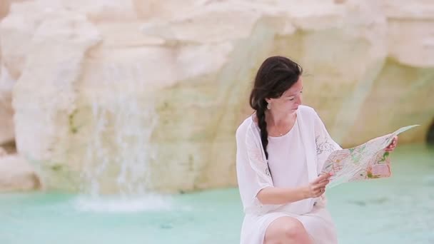Όμορφη γυναίκα κοιτάζει τουριστικό χάρτη της πόλης κοντά στο Trevi Fountain, Ρώμη, Ιταλία. Ευτυχισμένο κορίτσι απολαύσετε ιταλικές διακοπές στην Ευρώπη. — Αρχείο Βίντεο