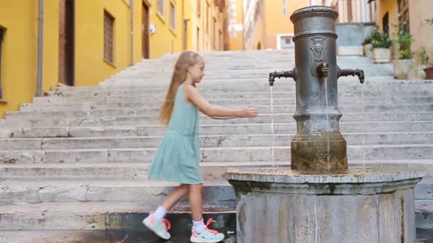 A kis imádnivaló lány vizet iszik a csapból kint a forró nyári napon Rómában, Olaszországban. — Stock videók