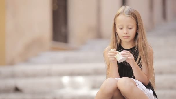 En söt liten flicka som äter glass utomhus på sommaren. Söt unge njuter av äkta italiensk gelato i Rom — Stockvideo