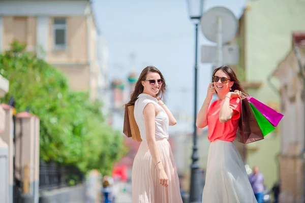 Glada unga kvinnor med shoppingkassar längs stadsgata. Försäljning, konsumism och människor-konceptet. — Stockfoto