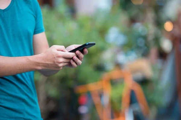 De close-up van mannelijke handen houdt zijn mobieltje buiten op straat. Man met mobiele smartphone. — Stockfoto