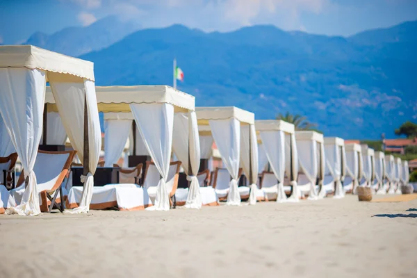 Wooden sunbeds in front of a turquoise sea in the evening light. Sunbeds in famous italian sand beach at Forte dei Marmi — Stock Photo, Image