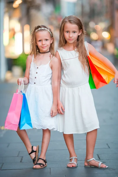 Adorable little girls on shopping. Portrait of kids with shopping bags in small italian town — Stock Photo, Image