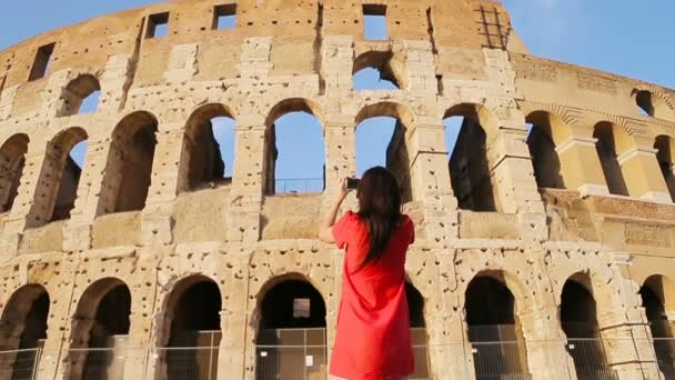 Ung kvinna fotograferar framför Colosseum i Rom, Italien. Flicka att göra fotografier för minnet av de mest populära destinationen i världen — Stockvideo