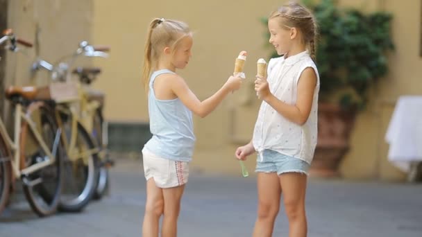Adorable little girls eating ice-cream outdoors at summer. Cute kids enjoying real italian gelato near Gelateria in Rome — Stock Video