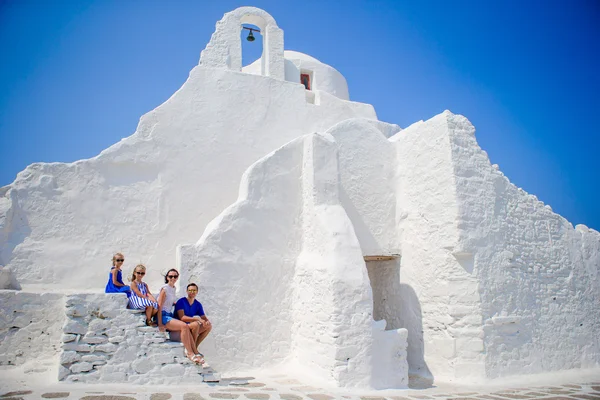 Rodinná dovolená v Evropě. Rodiče a děti sedí na schodech kostela Paraportiani na ostrově Mykonos v Řecku — Stock fotografie
