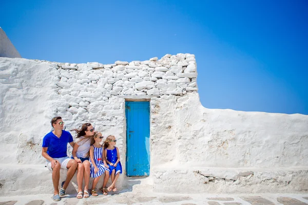 Rodinná dovolená v Evropě. Rodiče a děti na ulici typické řecké tradiční vesnice s bílými zdmi a barevnými dveřmi na ostrově Mykonos, v Řecku — Stock fotografie