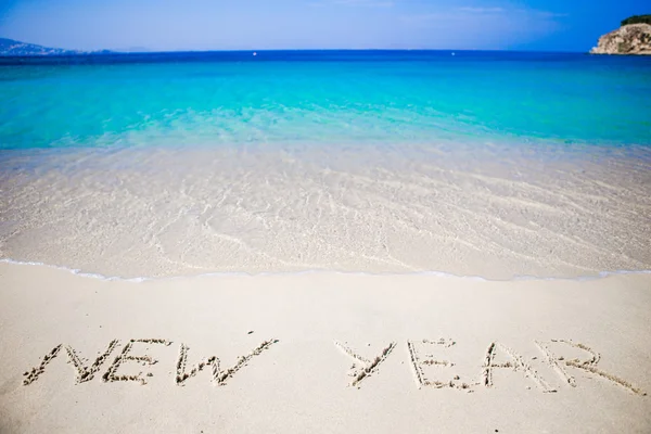 Feliz Año Nuevo escrito en la arena blanca —  Fotos de Stock