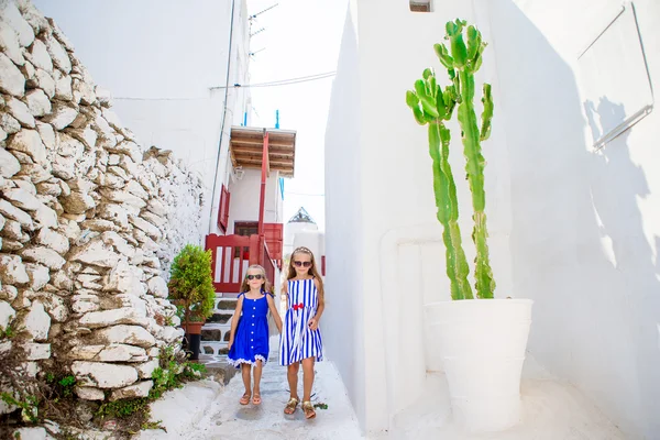 Due ragazze in abiti blu divertirsi all'aperto. Bambini in strada del tipico villaggio greco tradizionale con pareti bianche e porte colorate sull'isola di Mykonos, in Grecia — Foto Stock